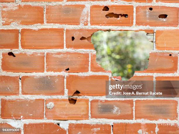 full frame of a facade of a wall with bricks with a big hole . high resolution photography. - adobe texture stockfoto's en -beelden