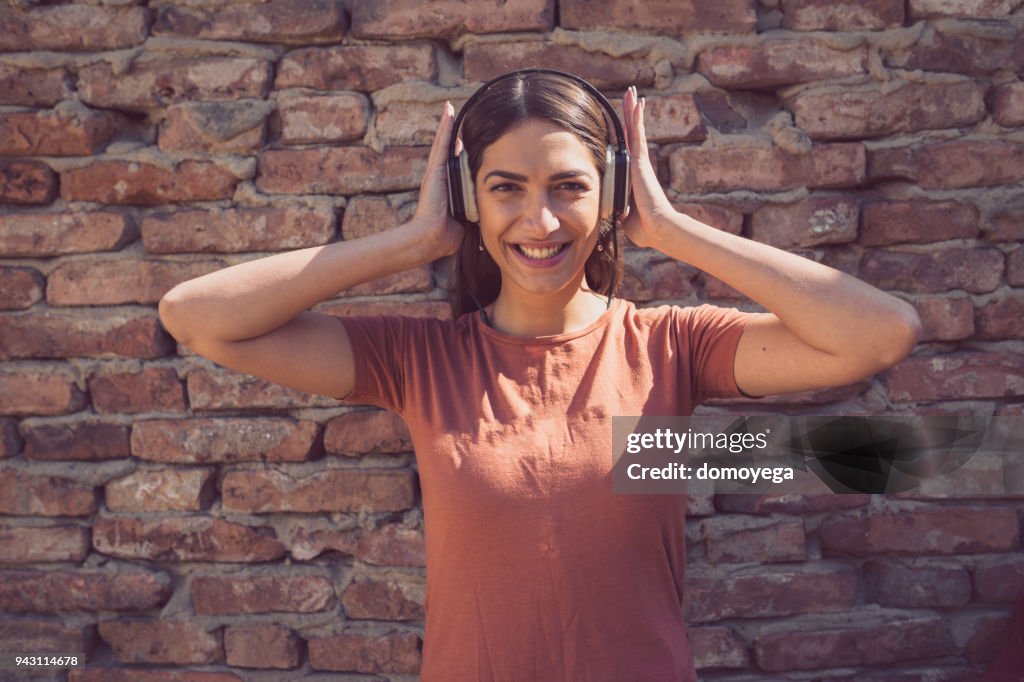 Beautiful woman with headphones listening to music outdoors