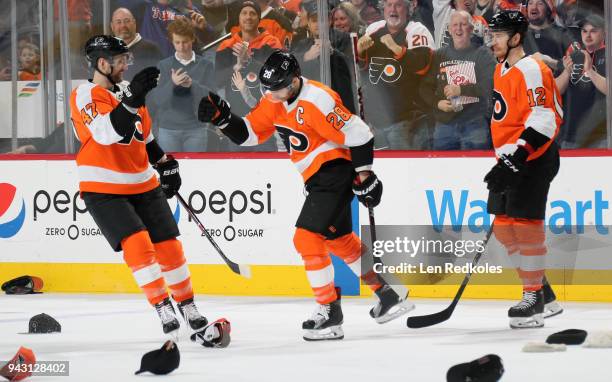 Hats litter the ice as Claude Giroux of the Philadelphia Flyers celebrates his third goal of the game against the New York Rangers with Andrew...