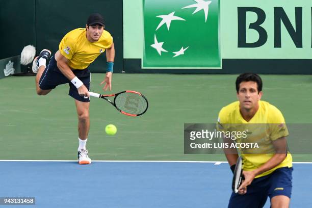 Brazilian tennis player Marcelo Demoliner serves next to his teammate Marcelo Melo against Colombian tennis players Juan Sebastian Cabal and Robert...
