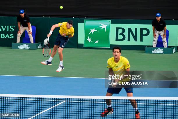 Brazilian tennis player Marcelo Demoliner serves next to teammate Marcelo Melo against Colombian tennis players Juan Sebastian Cabal and Robert Farah...
