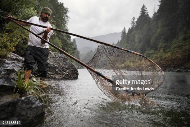 young adult native american man standing in shallow river fishing for sockeye salmon - native river stock-fotos und bilder