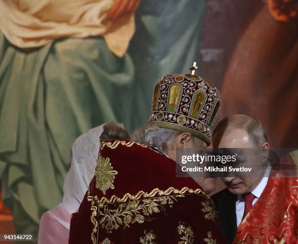 Russian President Vladimir Putin listens to Orthodox Patriarch Kirill as Prime Minister Dmitry Medvedev looks on during the Orthodox Easter service...