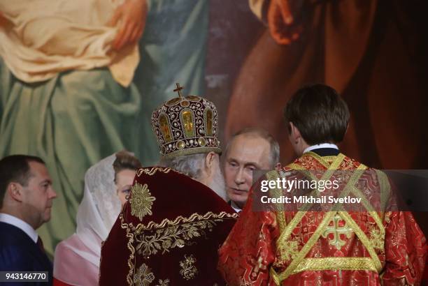 Russian President Vladimir Putin kisses Orthodox Patriarch Kirill as Prime Minister Dmitry Medvedev looks on during the Orthodox Easter service in...
