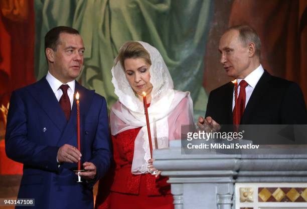 Russian President Vladimir Putin to Prime Minister Dmitry Medvedev as his wife Svetlana Medvedeva looks on during the Orthodox Easter service in the...