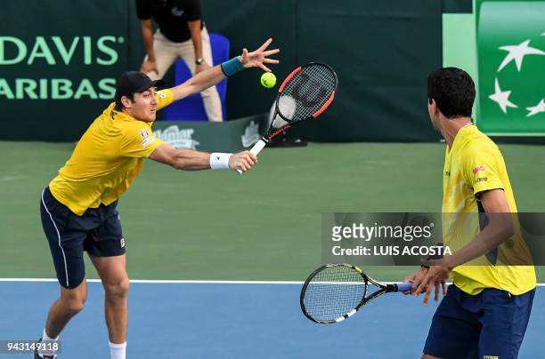 Brazilian tennis player Marcelo Demoliner returns a ball next to his teammate Marcelo Melo against Colombian tennis players Juan Sebastian Cabal and...