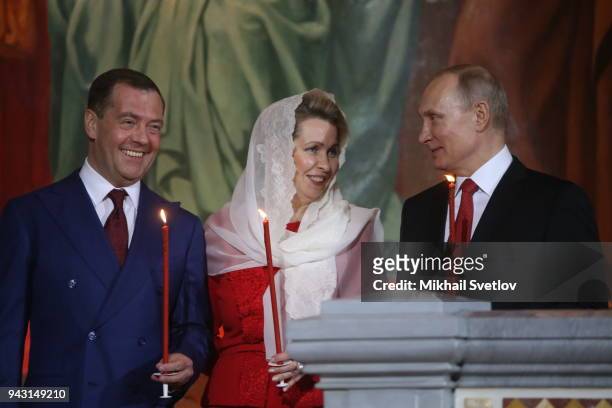 Russian President Vladimir Putin looks to Prime Minister Dmitry Medvedev as his wife Svetlana Medvedeva looks on during the Orthodox Easter service...