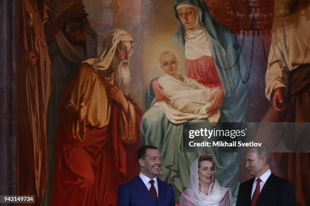 Russian President Vladimir Putin looks to Prime Minister Dmitry Medvedev as his wife Svetlana Medvedeva looks on during the Orthodox Easter service...