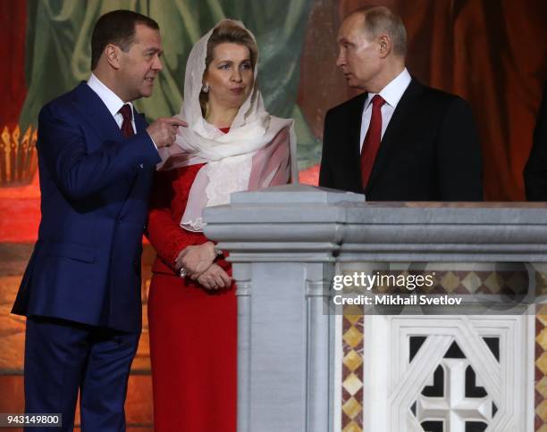 Russian President Vladimir Putin to Prime Minister Dmitry Medvedev as his wife Svetlana Medvedeva looks on during the Orthodox Easter service in the...