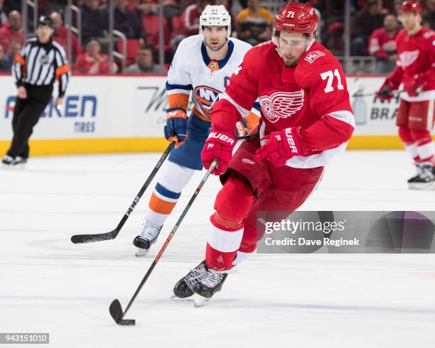 Dylan Larkin of the Detroit Red Wings skates up ice with the puck in front of John Tavares of the New York Islanders during an NHL game at Little...