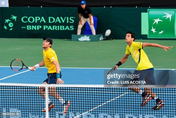 Brazilian tennis player Marcelo Demoliner and his teammate Marcelo Melo eye the ball during their Americas Zone Group I, 2nd round Davis Cup tennis...