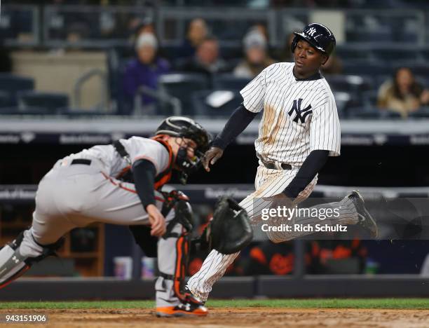 Didi Gregorius of the New York Yankees slides into home safely before the tag by catcher Chance Sisco of the Baltimore Orioles on a single by Neil...