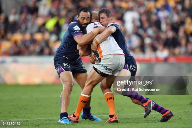 Robbie Rochow of the Tigers is tackled by Sam Kasiano of the Storm and Ryan Hoffman of the Storm during the round five NRL match between the Wests...