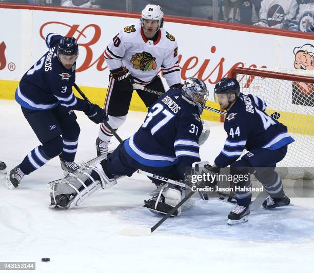 Tucker Poolman, Connor Hellebuyck and Josh Morrissey of the Winnipeg Jets and Brandon Saad of the Chicago Blackhawks follow a rebound during NHL...