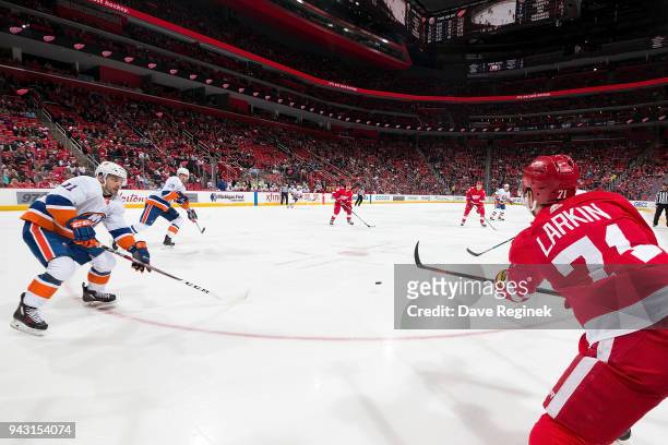 Dylan Larkin of the Detroit Red Wings passes the puck to teammate Darren Helm past the defense of Shane Prince and Brock Nelson of the New York...