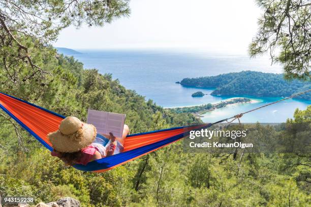 woman in a hammock with book on holiday - aegean turkey stock pictures, royalty-free photos & images