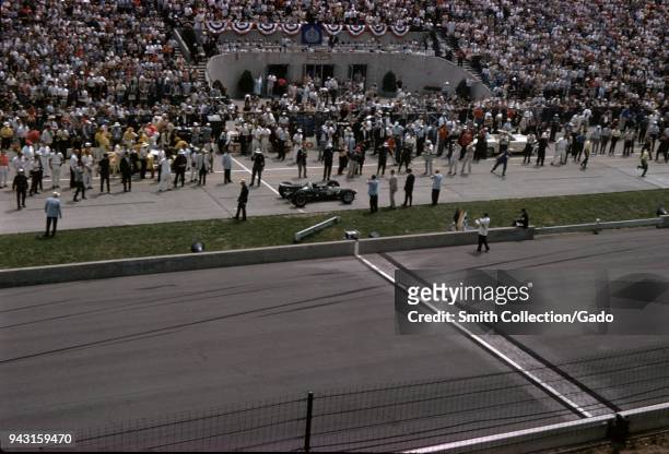 Race cars and spectators are visible at the Indianapolis 500 automobile race at Indianapolis Motor Speedway in Indianapolis, Indiana, 1965.