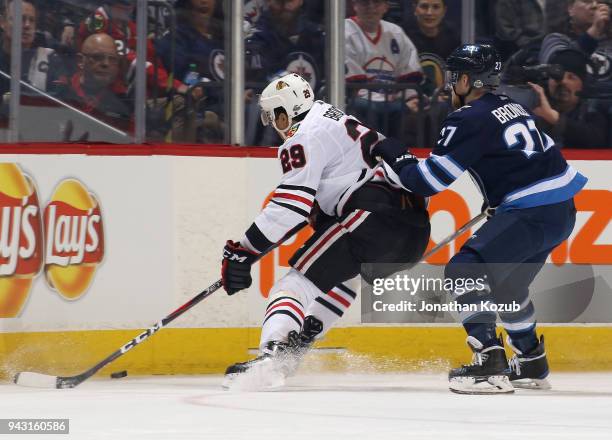 Andreas Martinsen of the Chicago Blackhawks plays the puck along the boards as Nikolaj Ehlers of the Winnipeg Jets defends during first period action...