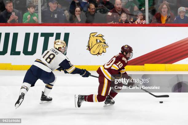 Kobe Roth of the Minnesota-Duluth Bulldogs skates past Jake Evans of the Notre Dame Fighting Irish during the Division I Men's Ice Hockey Semifinals...