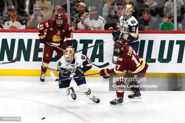 Blake Young of the Minnesota-Duluth Bulldogs races Jack Jenkins of the Notre Dame Fighting Irish for the puck during the Division I Men's Ice Hockey...