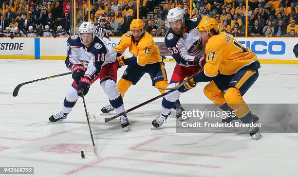 Pierre-Luc Dubois and David Savard of the Columbus Blue Jackets and Craig Smith and Scott Hartnell of the Nashville Predators chase a loose puck...