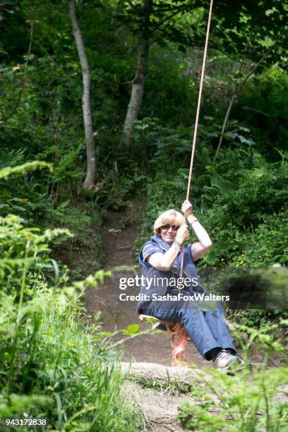 senior woman swinging on tree swing - sasha fox stock pictures, royalty-free photos & images