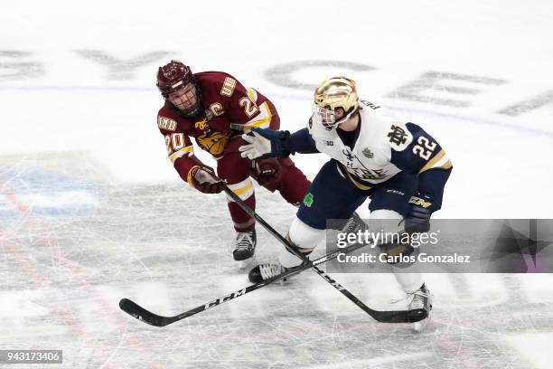 Andrew Peeke of the Notre Dame Fighting Irish and Karson Kuhlman of the Minnesota-Duluth Bulldogs battle for the puck during the Division I Men's Ice...