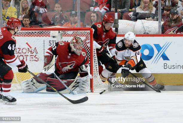 Adam Henrique of the Anaheim Ducks skates the puck in from behind goalie Antti Raanta of the Arizona Coyotes as Josh Archibald and Brendan Perlini of...