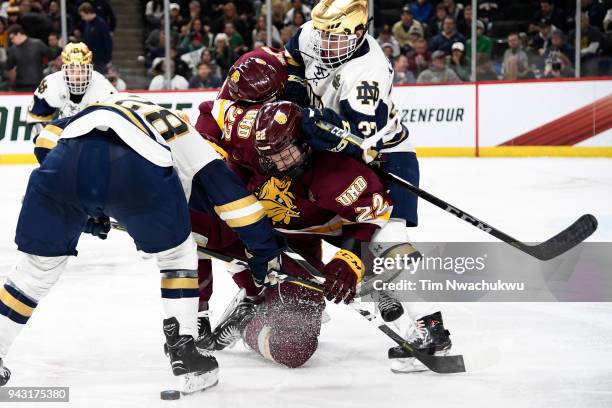 Jared Thomas of the Minnesota-Duluth Bulldogs and Jack Jenkins of the Notre Dame Fighting Irish battle for the puck during the Division I Men's Ice...