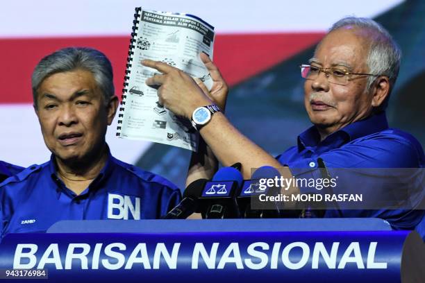 This picture taken on April 7, 2018 shows Malaysian Prime Minister Najib Razak pointing to the opposition manifesto before launching his coalition's...