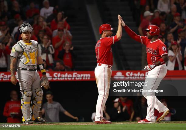 Justin Upton and Zack Cozart of the Los Angeles Angels of Anaheim high five at homeplate after Upton's two-run homerun as catcher Bruce Maxwell of...