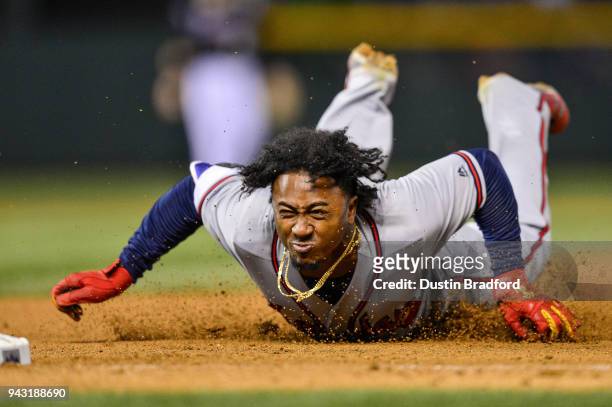 Ozzie Albies of the Atlanta Braves dives back to first base to avoid being doubled off in the ninth inning of a game against the Colorado Rockies at...