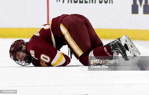 Kobe Roth of the Minnesota-Duluth Bulldogs is on the ice in pain after a hit by Justin Wade of the Notre Dame Fighting Irish in the first perod...