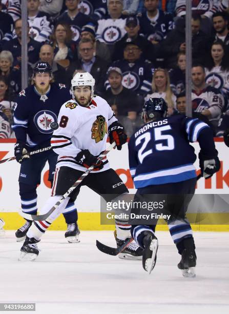 Nick Schmaltz of the Chicago Blackhawks and Paul Stastny of the Winnipeg Jets eye the flying puck during third period action at the Bell MTS Place on...