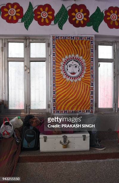 This photo taken on April 7 shows an Indian man takaking a nap in a waiting room painted with Mithila or Madhubani paintings at Madhubani railway...