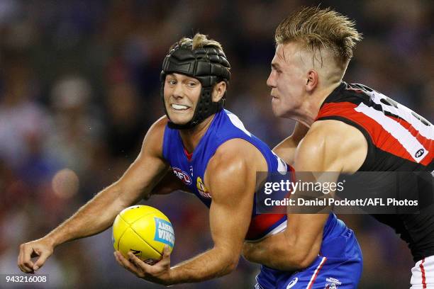 Caleb Daniel of the Bulldogs handpasses the ball whilst being tackled by Joshua Begley of the Bombers during the round three AFL match between the...