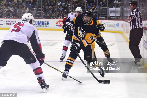 Zach Aston-Reese of the Pittsburgh Penguins shoots the puck against Cody Ceci of the Ottawa Senators at PPG PAINTS Arena on April 6, 2018 in...