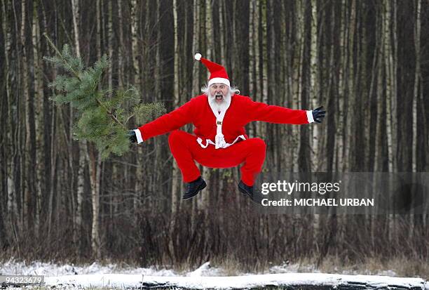 German cycling fan Didi Senft, also known as El Diablo, jumps in the air with a Christmas tree in a forest near Chorin eastern Germany on December 4,...