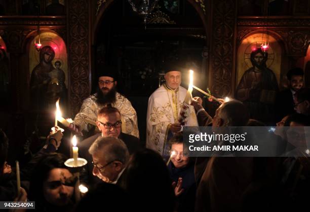 Egyptian Greek Orthodox priests extend their candles to light up for worshippers during the midnight Easter Saturday vigil at the Greek Orthodox...