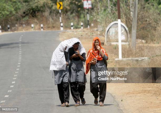 Young girl students cover their head and face in cloths to protect themselves from the Sun as they walks on road to return back home in the afternoon...