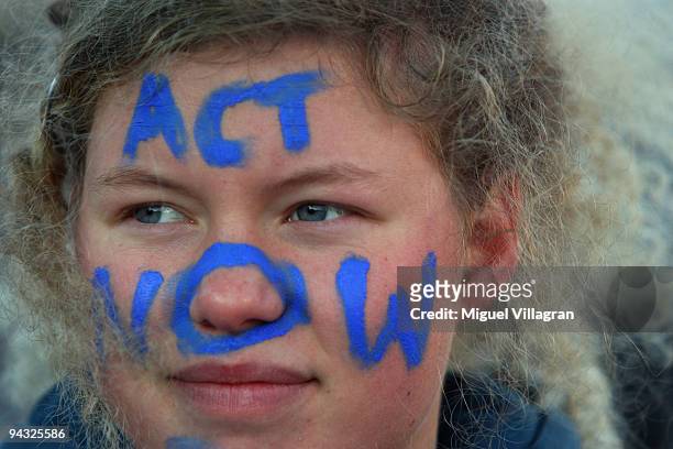 Protestor with the painting 'Act now" on her face takes part in a protest march towards the United Nations Climate Change Conference 2009 at the...