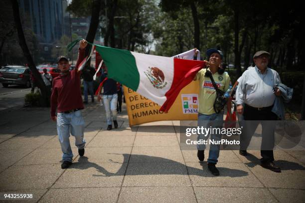 Group of migrants, hold an Mexican flag as part of the the annual Stations of the Cross caravan march for migrants' rights, during a protest in...