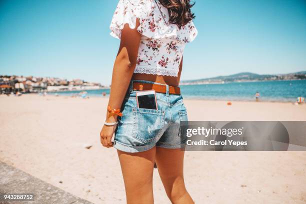 woman in jeans shorts with the phone in pocket - hot blue jeans foto e immagini stock