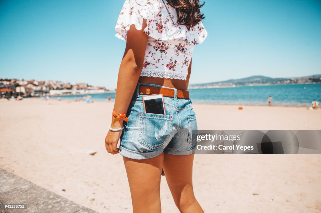 Woman  in jeans shorts with the phone in pocket