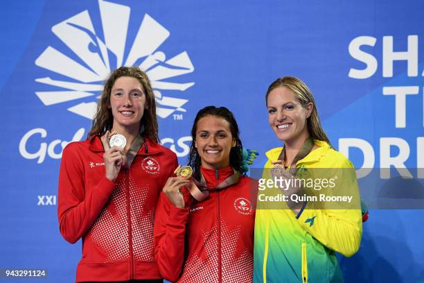 Silver medalist Taylor Ruck of Canada, gold medalist Kylie Masse of Canada and bronze medalist Emily Seebohm of Australia pose during the medal...