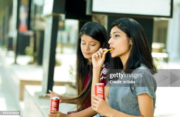 young girls eating potato chips and holding drink can - all you can eat stock pictures, royalty-free photos & images