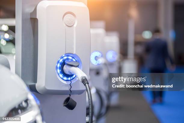 power supply for electric car charging. electric car charging station. close up of the power supply plugged into an electric car being charged. - renewable energy battery stock pictures, royalty-free photos & images