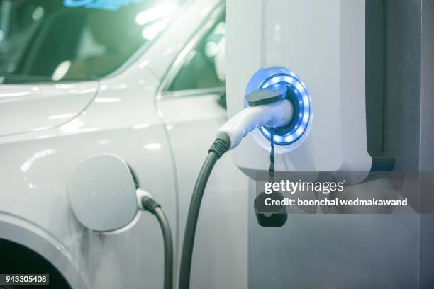 power supply for electric car charging. electric car charging station. close up of the power supply plugged into an electric car being charged. - concept car fotografías e imágenes de stock