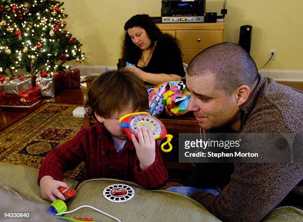 Army 1st Heavy Brigade Combat Team Captain Timothy Sands watches his son Ian play with a gift while he and his wife Army Capt. Angela Sands celebrate...