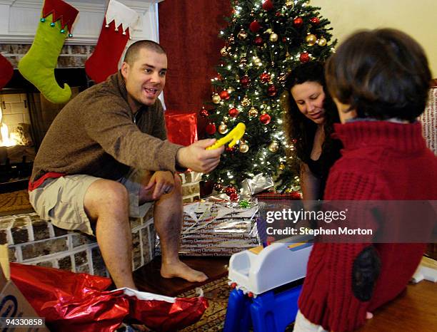 Army 1st Heavy Brigade Combat Team Captain Timothy Sands hands his son Ian a gift while he and his wife Army Capt. Angela Sands celebrate Christmas...